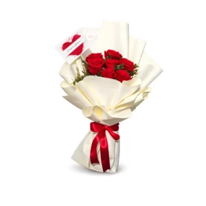 A bouquet of vibrant red roses elegantly wrapped in crisp white paper.