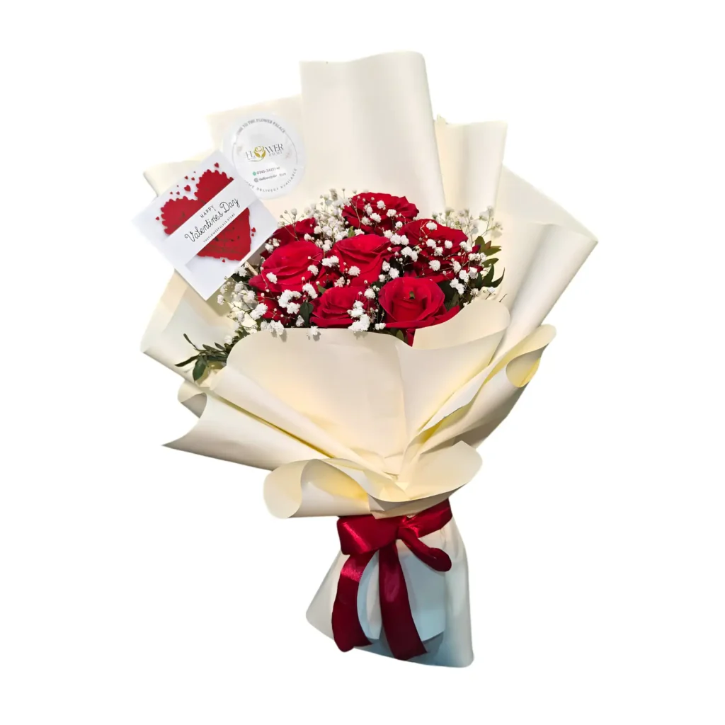 A bouquet of vibrant red roses wrapped in white paper, showcasing their lush petals and green leaves.